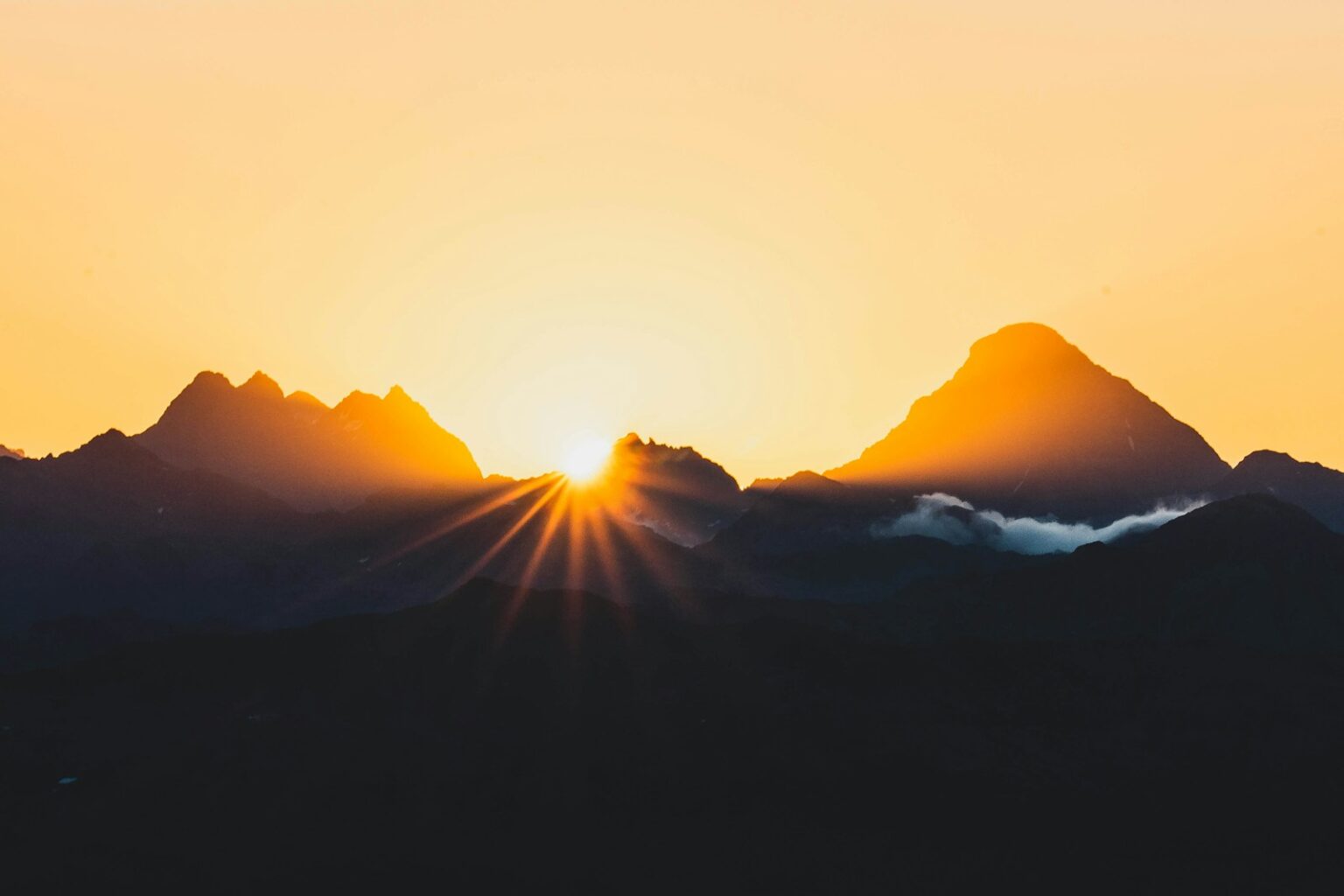 Sun setting behind mountains, creating a beautiful glow.